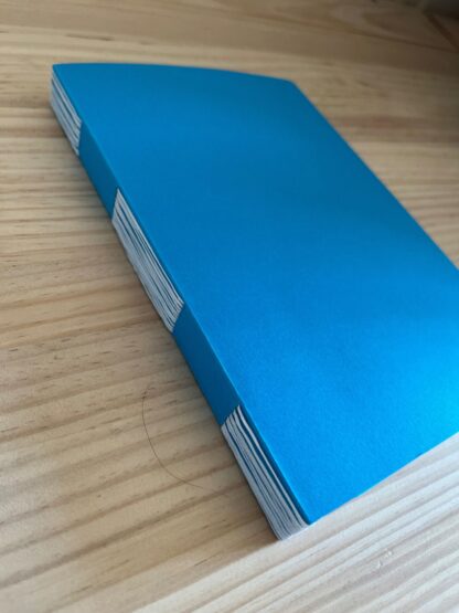 Carnet à couverture bleue et à reliure à fente avec un fil blanc posé à plat et fermé